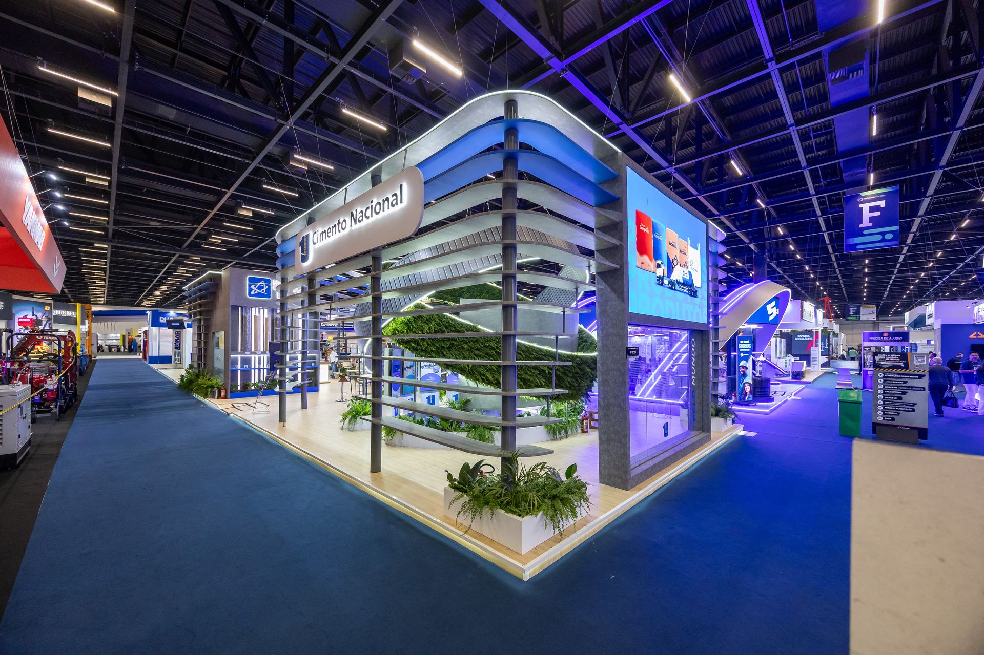 Estande Cimento Nacional na Concrete Show 2025 — vista diagonal do pavilhão com iluminação azul e estrutura curva em camadas