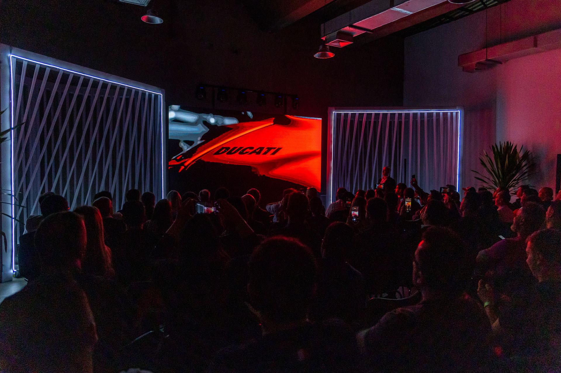 O reveal da Panigale V4 S — Ducati iluminada, plateia em silhueta dramática