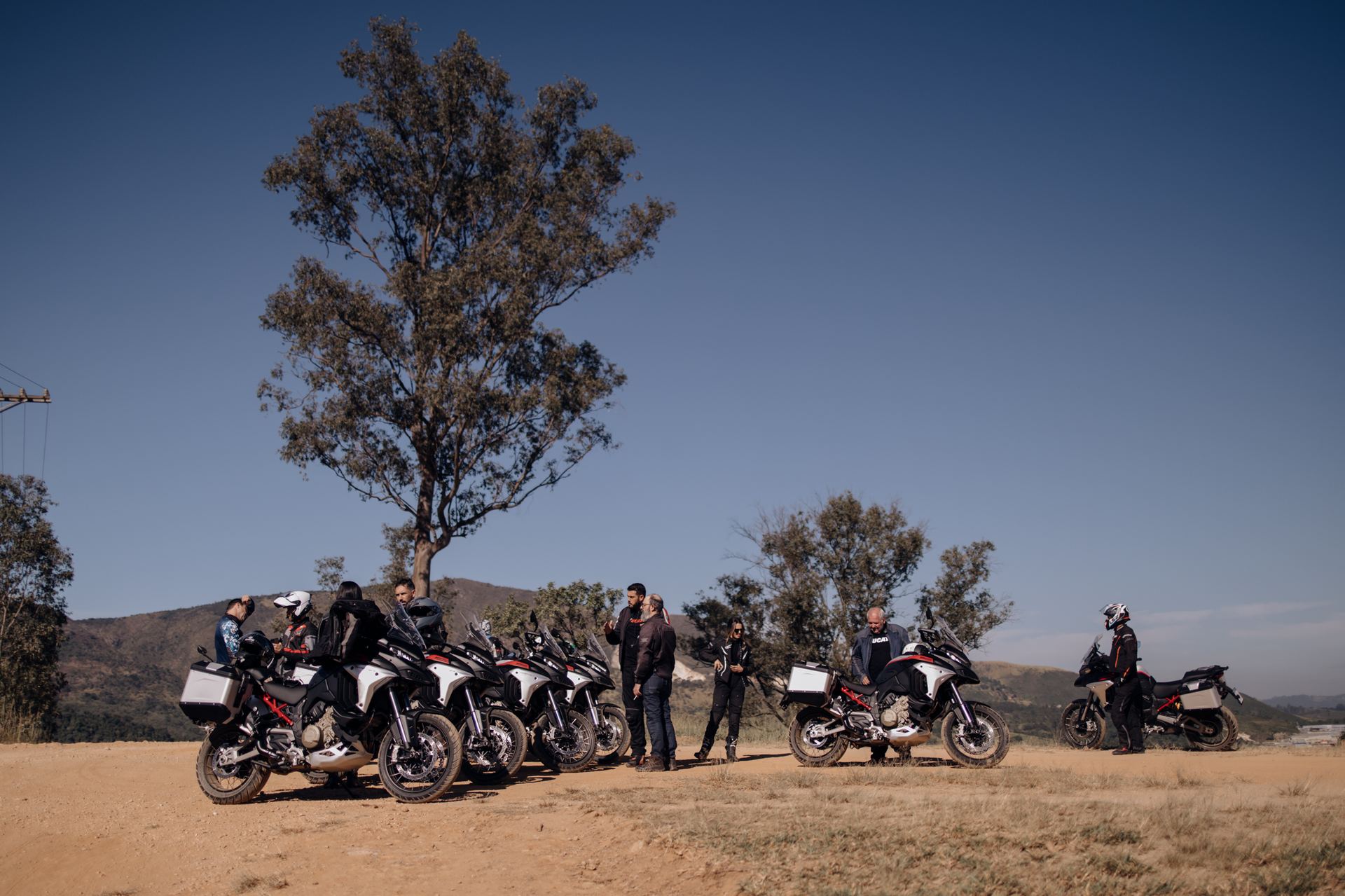 Grupo de participantes com motos Ducati no trecho de terra do percurso