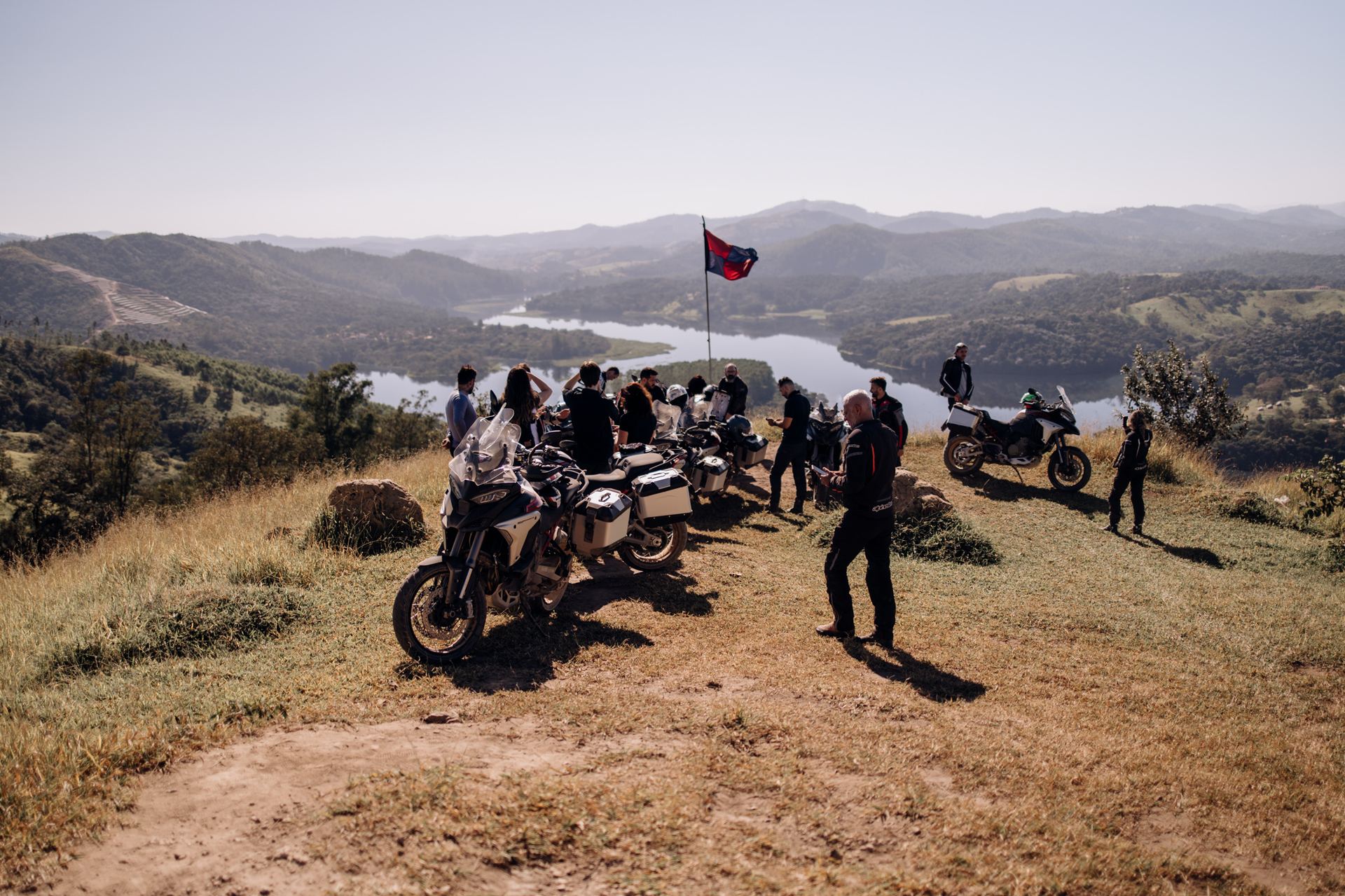 Grupo de participantes no mirante com bandeira Ducati e vista para o reservatório