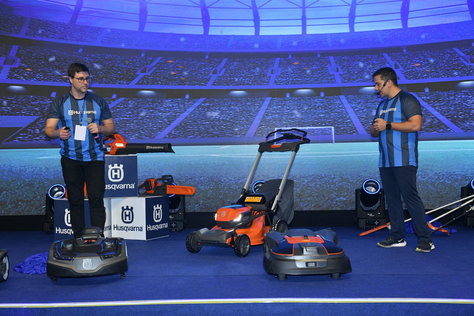 Lineup de produtos Husqvarna apresentados no palco — cortador, motosserra e soprador