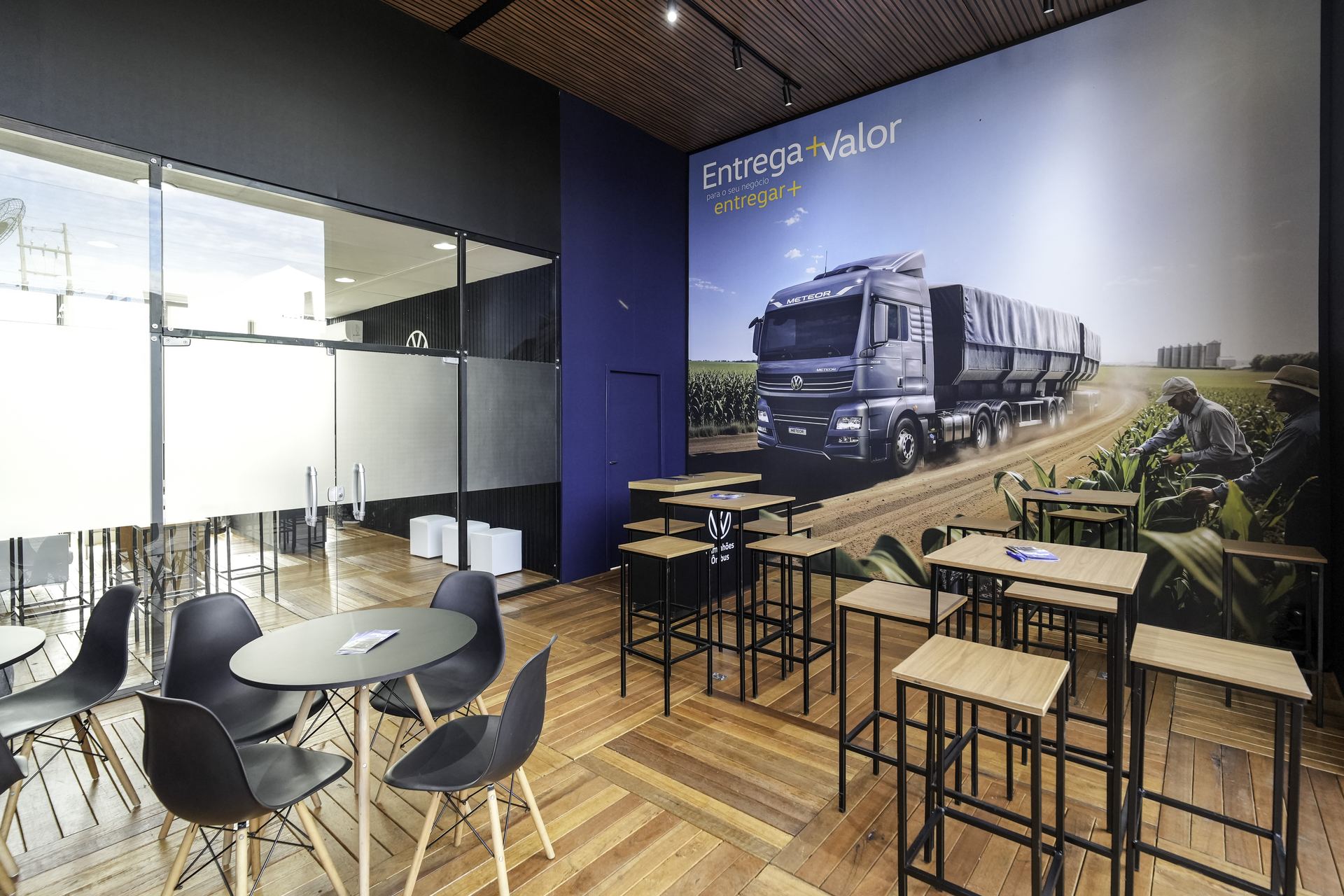 Área Entrega+Valor — mesas e painel Meteor no interior do estande