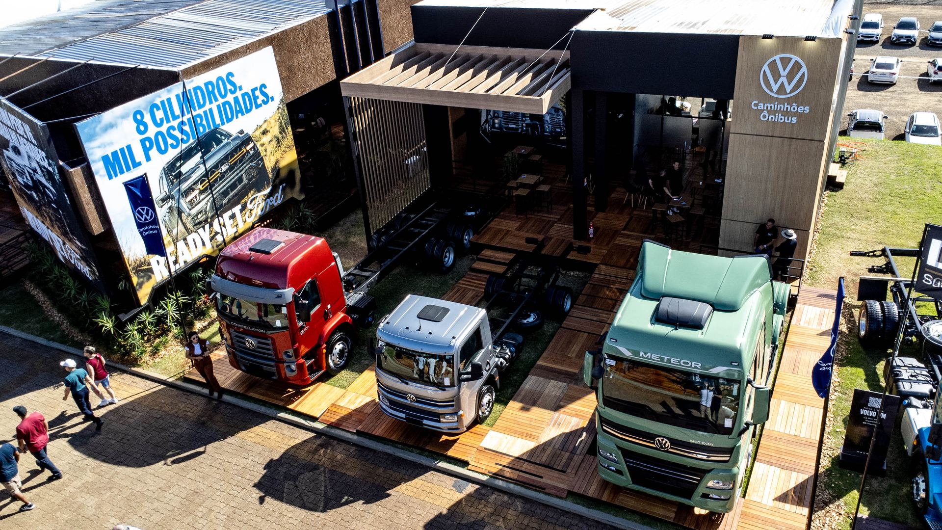 Vista aérea drone do estande VWCO na Expodireto 2026 — frota exposta no deck de madeira