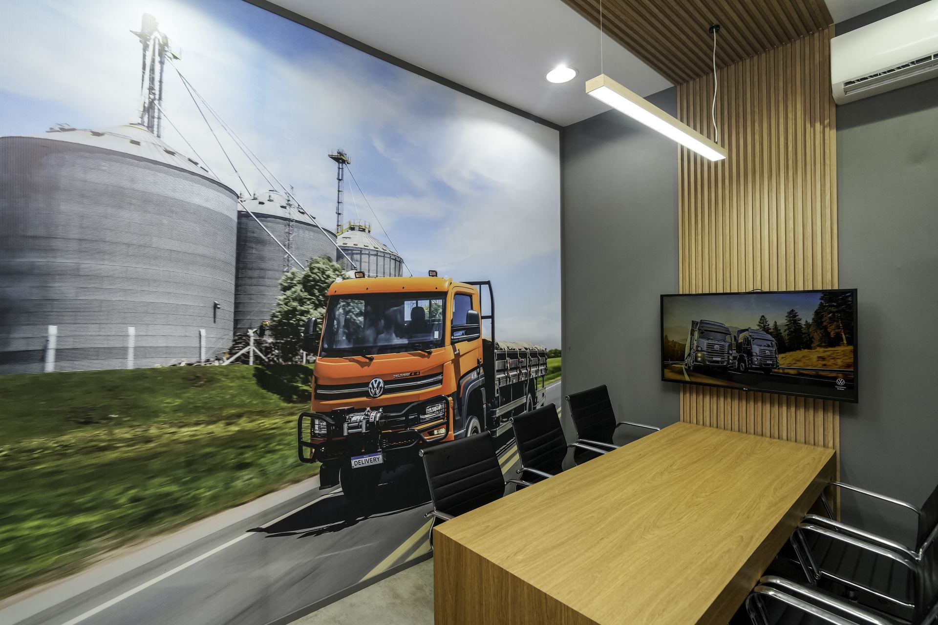 Sala de reunião interna do estande VWCO — mural Delivery e mesa executiva